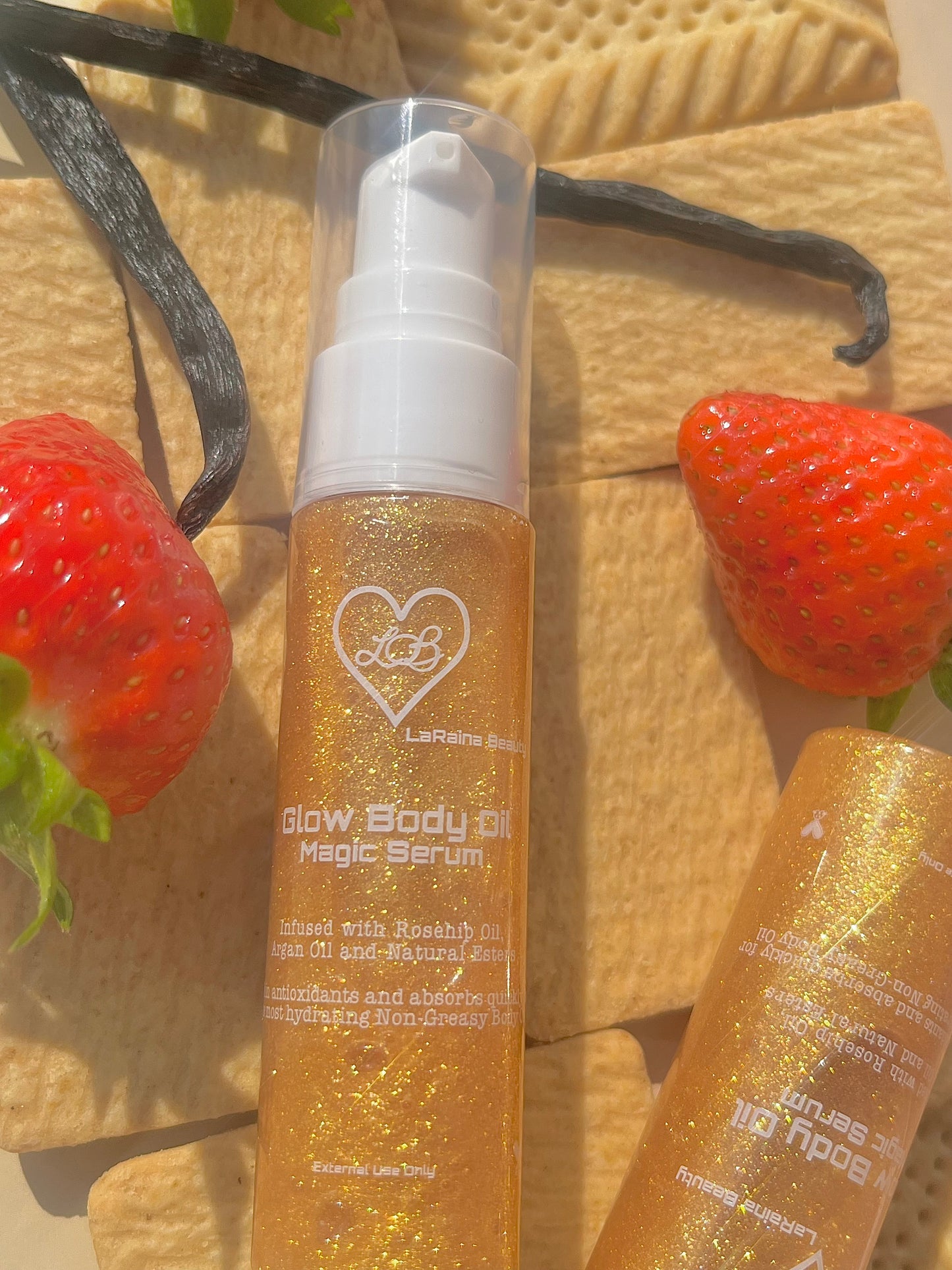 Gold bottle of 'Glow Body Oil Magic Serum' with strawberries and vanilla beans on a edible surface