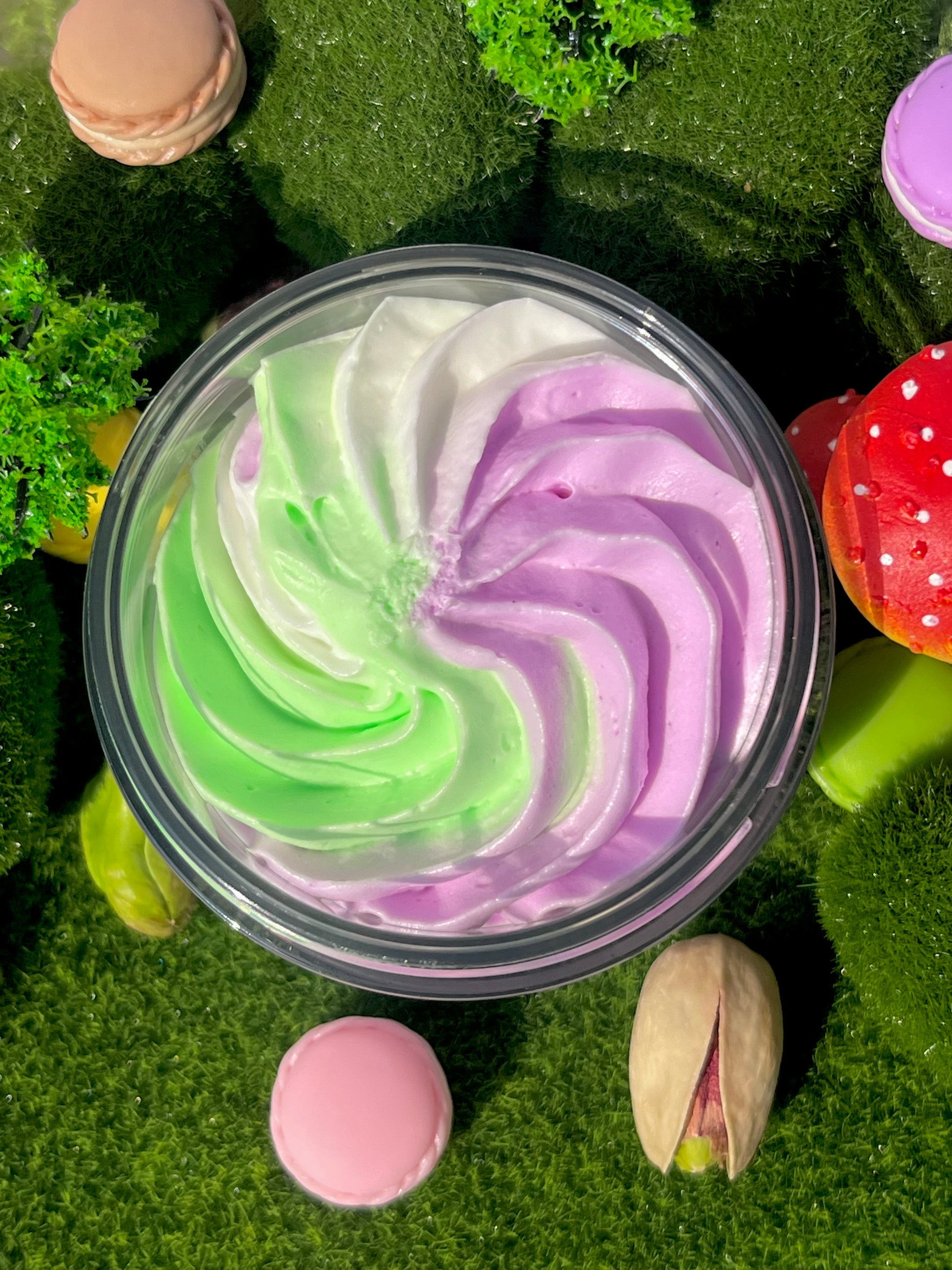 Colourful swirled body butter in a container on a green textured background with decorative elements.